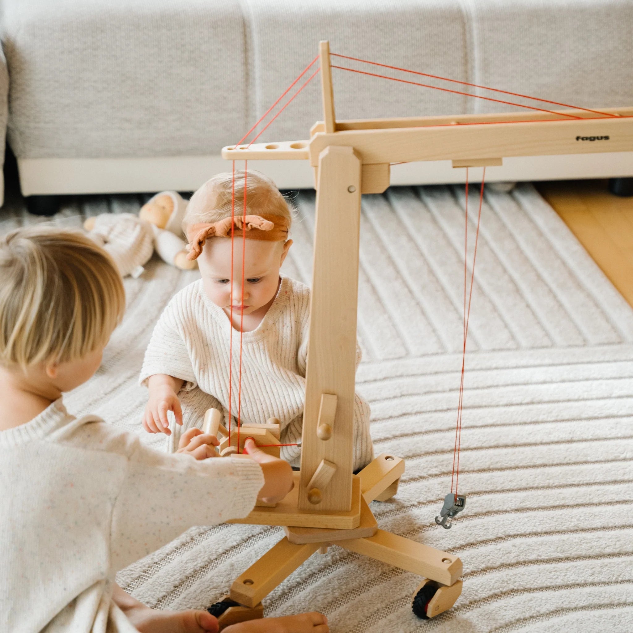 Zwei Kinder spielen mit einem hohen Holzkran
