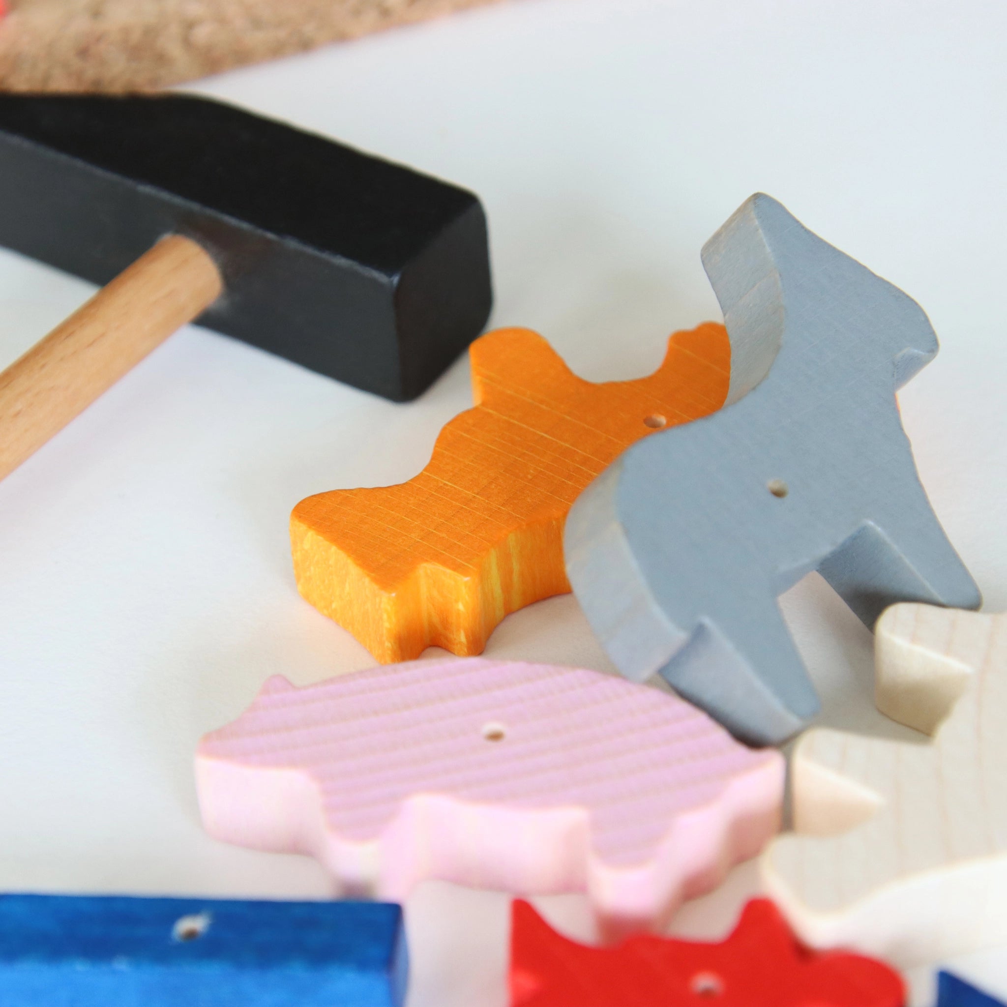 Hämmerchenspiel: Ein Spielset mit einem kleinen Hammer aus Holz mit schwarzem Kopf und bunten, tierförmigen Holzblöcken, das handwerkliches Geschick und Motorik fördert, hergestellt in Deutschland.