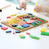 Hämmerchenspiel aus Kork und Holz: Ein Kinder-Bastelset auf einem Tisch, bestehend aus einem Korkbrett mit bunten Holzformen, die mit Nägeln fixiert werden. Kleine Hände positionieren Teile, ein Holzhammer liegt bereit.