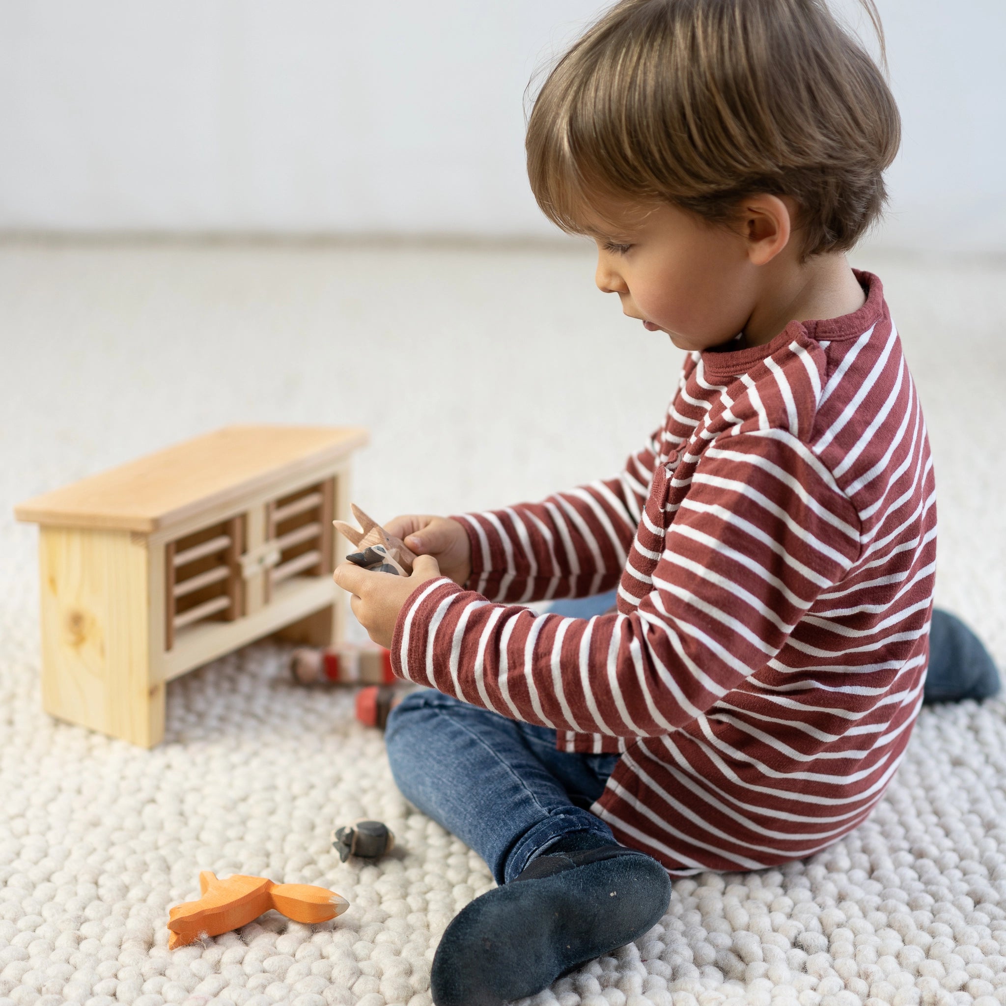 Hasenstall aus massivem Fichtenholz mit Leinöl, spielend von einem Kind genutzt. Zwei Boxen zum Öffnen und Schließen, ideal für kleine Holzhasen. Hergestellt in einer deutschen Holzmanufaktur.