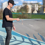 Mann mit schwarzem Hut und Sonnenbrille spielt Geschicklichkeitsspiel: Kugelfangspiel aus massivem Buchenholz, fördert Geschicklichkeit und Koordination. Ideal für Kinder und Erwachsene, hergestellt in Vorarlberg, Österreich.