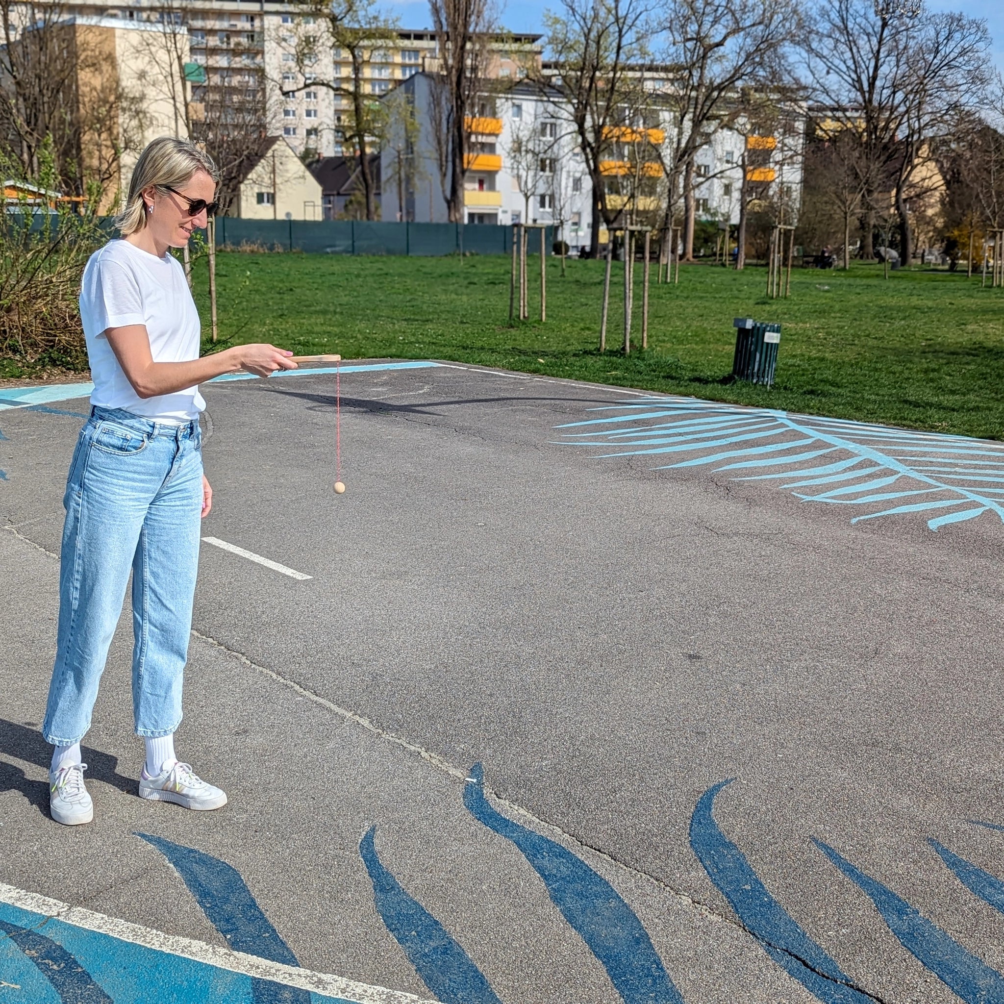 Geschicklichkeitsspiel: Kugelfangspiel aus massivem Buchenholz wird von Frau gehalten. Fördert Geschicklichkeit und Koordination, ideal für Kinder und Erwachsene. Produkt der Eigenmarke Waelderspielzeug, hergestellt in Vorarlberg, Österreich.