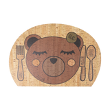 Kinder Tischset: Enjoying Bear, ein charmantes, Montessori-inspiriertes Design aus wasserabweisendem Korkleder, zeigt ein lächelndes Bärengesicht auf einem Holzbrett mit passendem Löffel und Gabel, perfekt für den Familientisch.