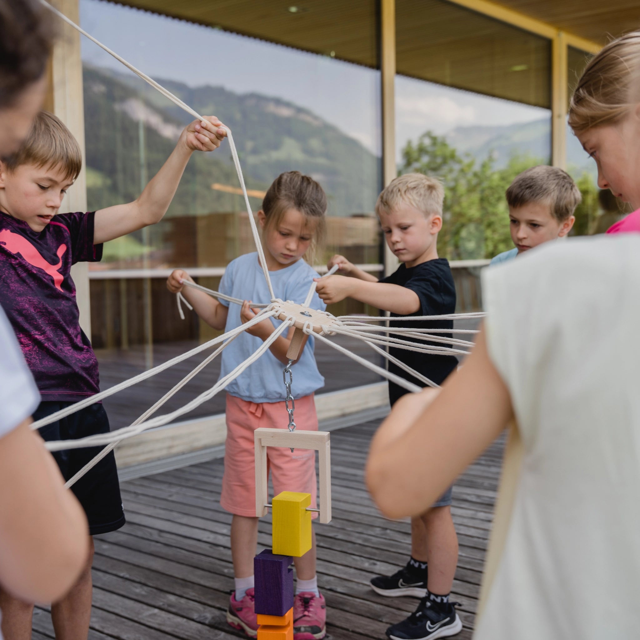 Kinder spielen mit dem Teamspiel: Kinder-Fröbelturm bunt aus massivem Buchenholz, geeignet für 4 bis 24 Spieler im Alter von 4 bis 7 Jahren, ideal für Teamaktivitäten auf dem Spielplatz.