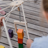 Kind spielt mit dem Teamspiel: Kinder-Fröbelturm bunt aus massivem Buchenholz, geeignet für 4 bis 24 Spieler im Alter von 4 bis 7 Jahren, inklusive praktischem Transportbeutel.