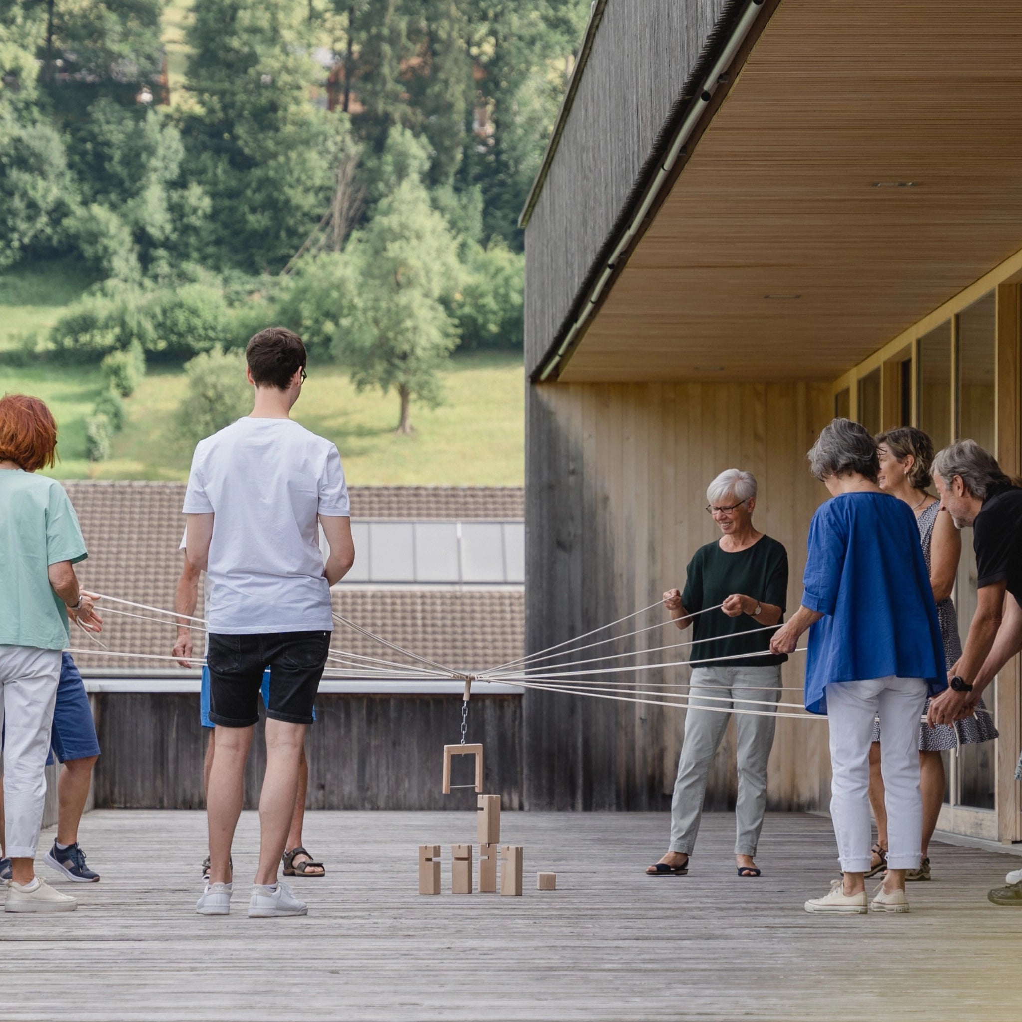 Teamspiel: Fröbelturm natur, ein spannendes Gruppenspiel aus massivem Buchenholz, wird von mehreren Personen im Freien gespielt, mit Seilen werden die Holzteile gemeinschaftlich bewegt. Ideal für 4 bis 24 Spieler.