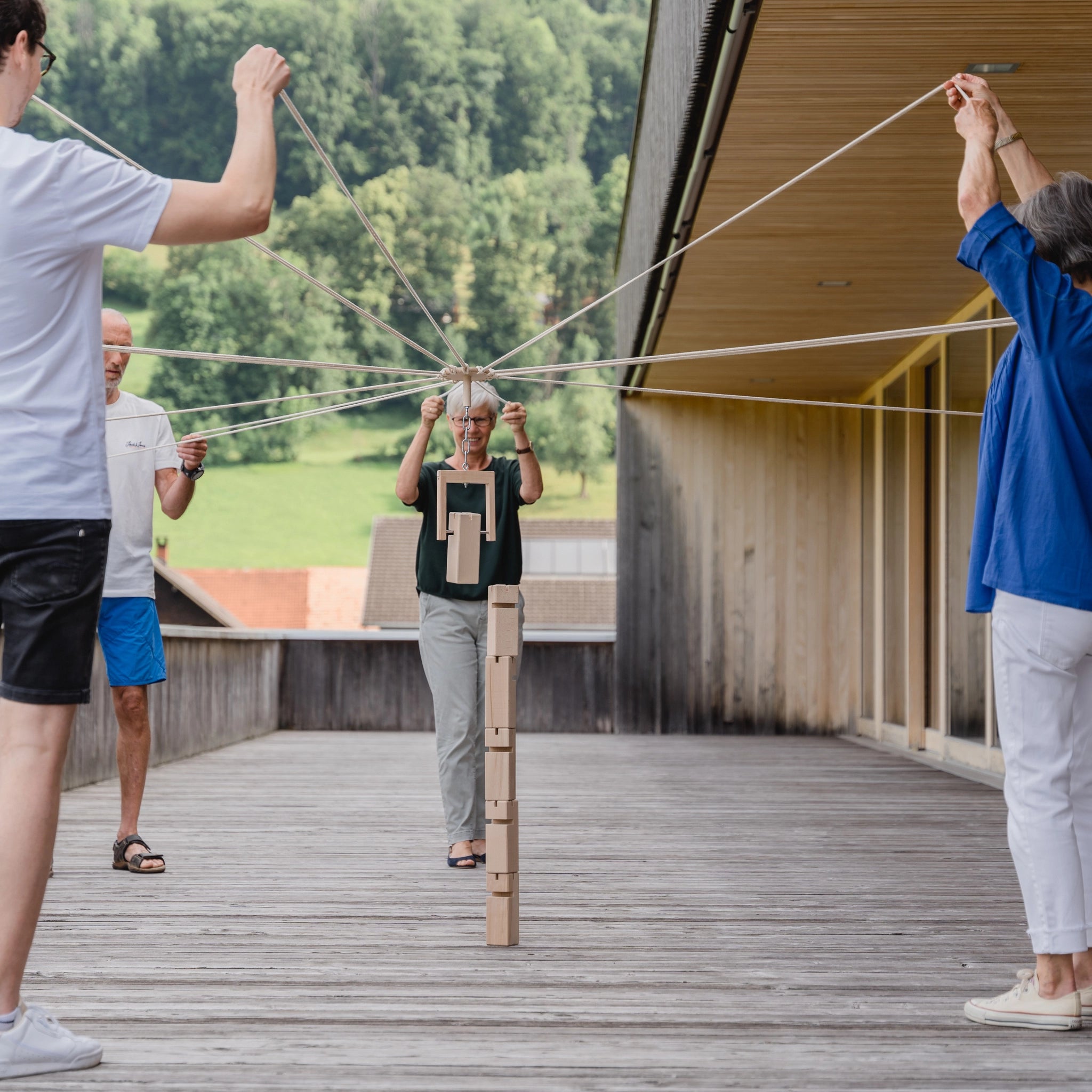 Teamspiel: Fröbelturm natur aus massivem Buchenholz, im Einsatz von mehreren Personen auf einem Deck, zeigt das interaktive Spiel in Aktion, ideal für Gruppen von 4 bis 24 Spielern.