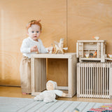 Großer Kinderhocker aus massivem Eschenholz neben spielendem Baby mit Holzspielzeug, geeignet als Beistelltisch, hergestellt in Vorarlberg. Perfekt für modernes, nachhaltiges Wohnen bei KLICKKLACK.