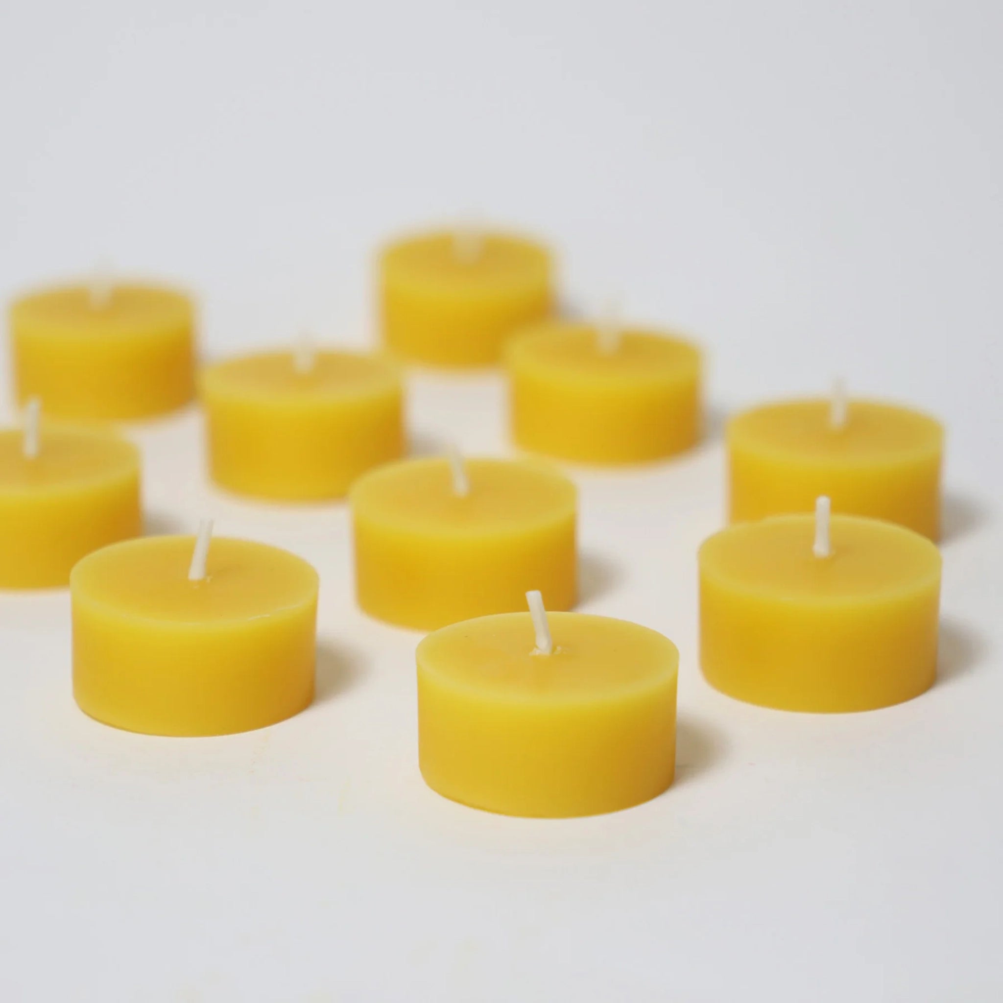 Steckfigur: Teelichter, eine Kollektion kleiner, runder Teelichter mit weißen Dochten, liebevoll hergestellt in einer deutschen Manufaktur, präsentiert auf einem schlichten weißen Untergrund.