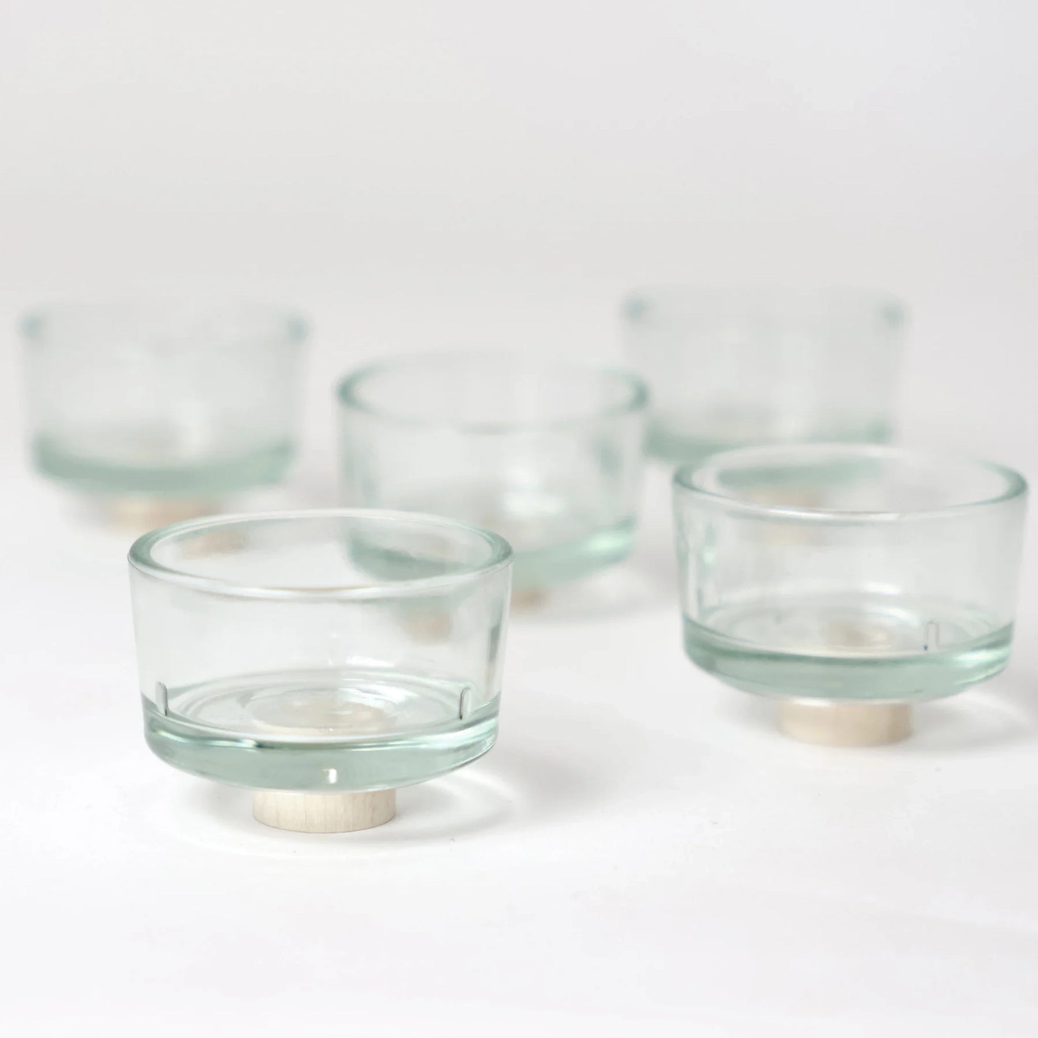 Fünf identische Steckfigur: Teelichthalter Glas auf runden Holzbasen, sorgfältig in einer kleinen deutschen Manufaktur gefertigt, vereinen minimalistisches Design und nachhaltige Produktion auf einem schlichten weißen Hintergrund.