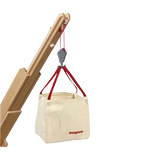 Zubehör: Big-Bags an einem kleinen Holzkran mit Flaschenzug und rotem Seil, das eine quadratische, naturfarbene Canvas-Tasche mit roten Griffen und fagus-Aufdruck hebt, ideal für kreative Baustellenspiele.