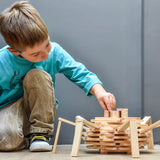 Junge beim Spielen mit Bausteine: 200er Box, baut Gitterstruktur aus naturfarbenen KAPLA-Plättchen, fördert Kreativität und räumliches Denken, hergestellt aus nachhaltigem Pinienholz in Frankreich.