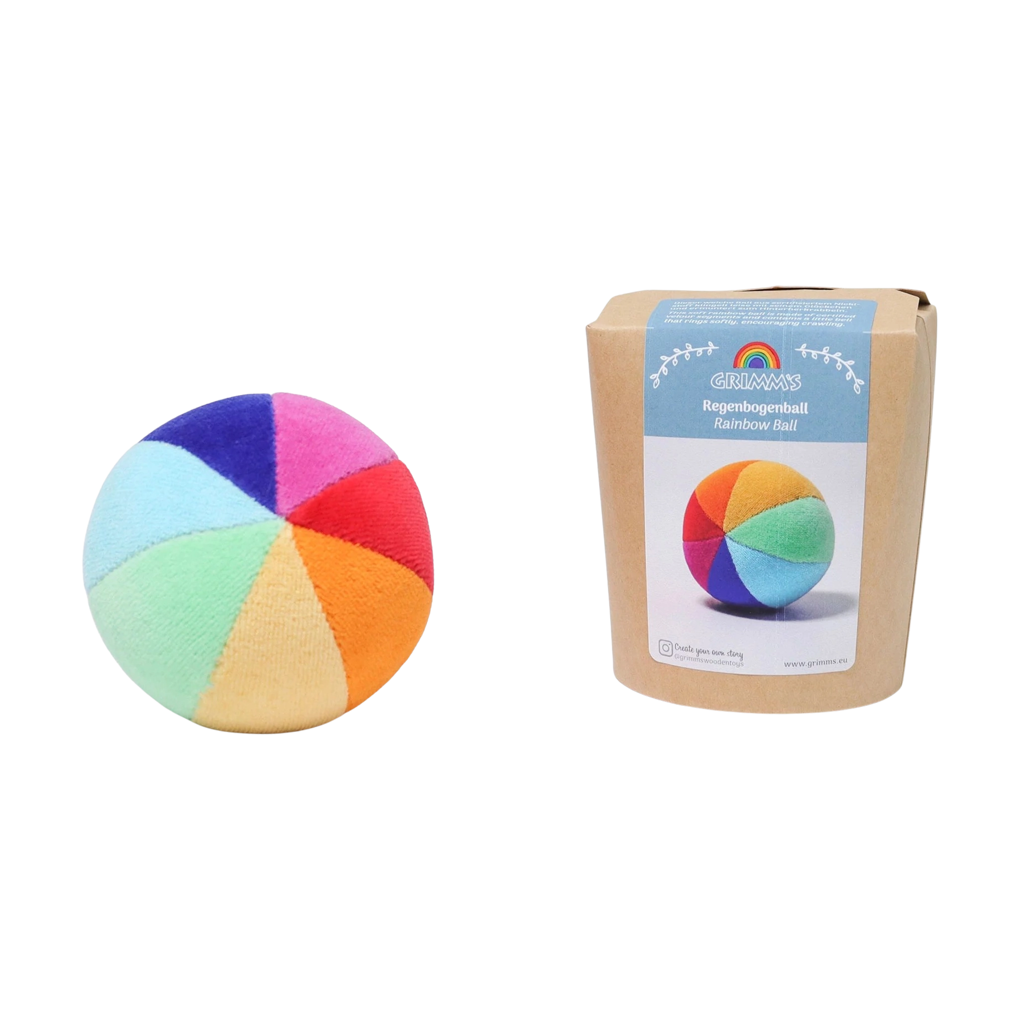Der Regenbogenball aus weichem Nikistoff, bestehend aus acht bunten Segmenten, liegt neben seiner umweltfreundlichen Verpackung. Ein Glöckchen im Inneren fördert das Greifen und die Feinmotorik von Babys.