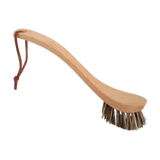 Spülbürste mit langem Holzgriff und steifen Borsten, ideal zum Schrubben von Töpfen und Pfannen. Ein Lederband am Griffende ermöglicht praktisches Aufhängen, passend zum nachhaltigen Designanspruch von KLICKKLACK.