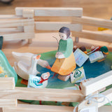 Holztier: Gänseküken Kopf hoch aus hochwertigem Ahornholz, handbemalt, ideal für kreatives Kinderspiel, auf einem Tisch neben einer Holzfigur einer Frau und anderen Holzspielzeugen platziert.