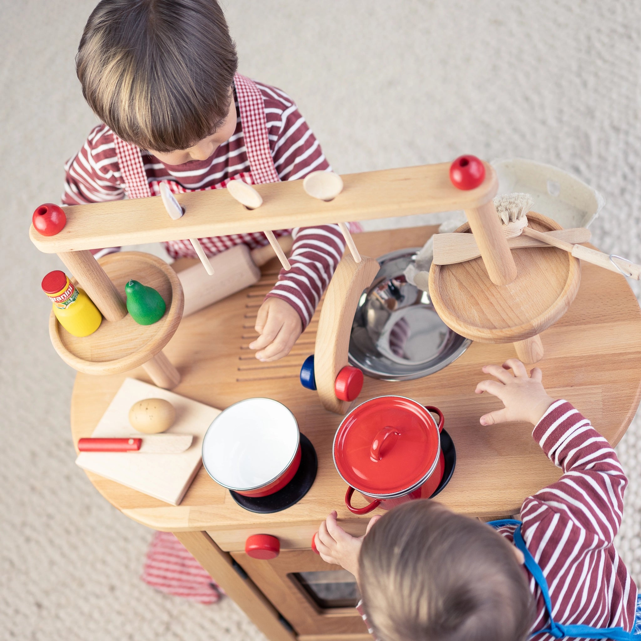 Kinderkochlöffel aus unbehandeltem Buchenholz, ideal für kleine Köche. Zwei Kinder spielen damit, was den robusten, hochwertigen Löffel in Aktion zeigt. Hergestellt in einer deutschen Manufaktur.