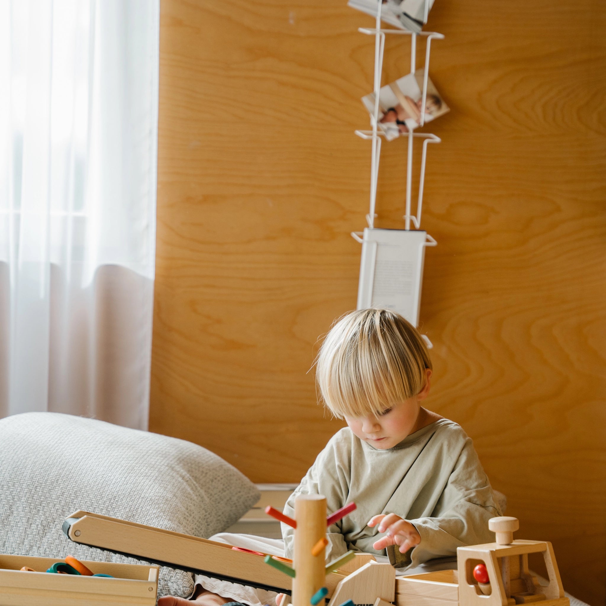 Holzfahrzeug: Unimog aus massivem Buchenholz, lenkbares Spielzeug mit robuster Ladefläche. Ein Kind spielt damit drinnen, was die Vielseitigkeit und handwerkliche Qualität des Produkts aus Deutschland zeigt.