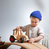 Holzfahrzeug: Schlepper aus massivem Buchenholz zeigt ein Kind, das mit einem präzise lenkbaren Spielzeugtraktor spielt, inklusive zweier Fahrerfiguren. Kompatibel mit allen Fagus-Anhängern, hergestellt in Deutschland.