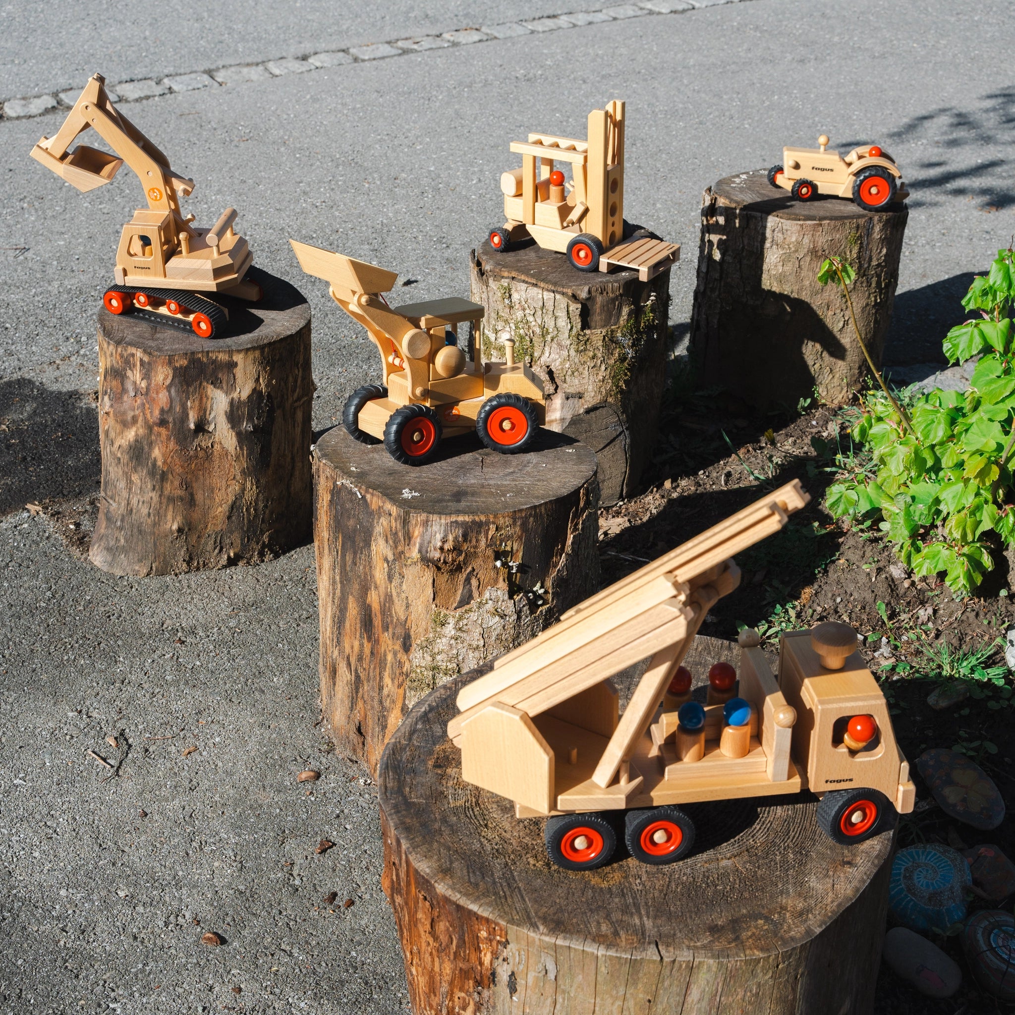 Holzfahrzeug: Gabelstapler aus massivem Buchenholz auf einem Baumstumpf, mit lenkbarer Kurbel und zwei Fahrerfiguren. Nachhaltig in Deutschland hergestellt, ideal für moderne, umweltbewusste Zielgruppen.