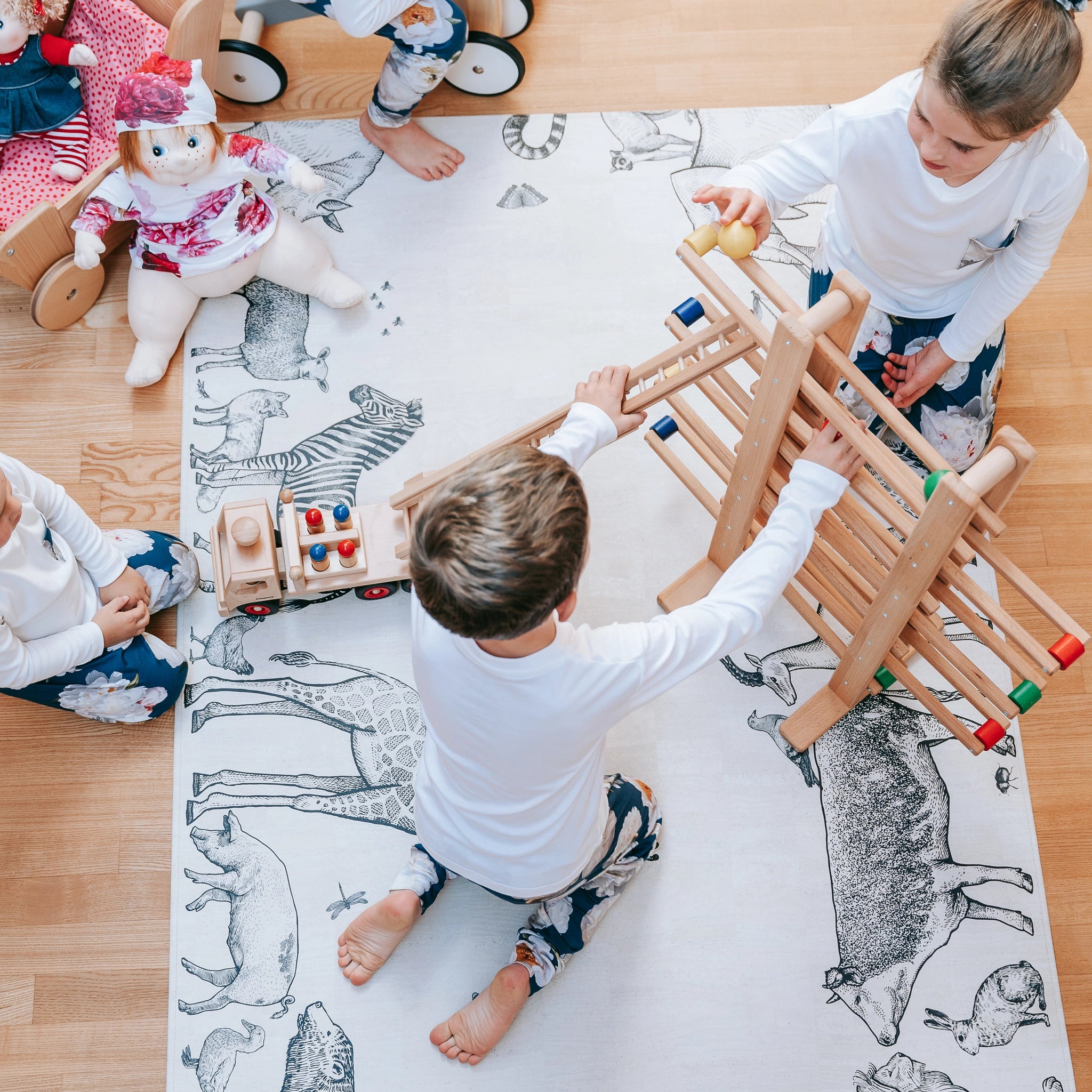 Holzfahrzeug: Feuerwehrauto aus massivem Buchenholz mit drehbarer, höhenverstellbarer Leiter und sechs Feuerwehrleuten, dargestellt beim Spielen von Kindern.