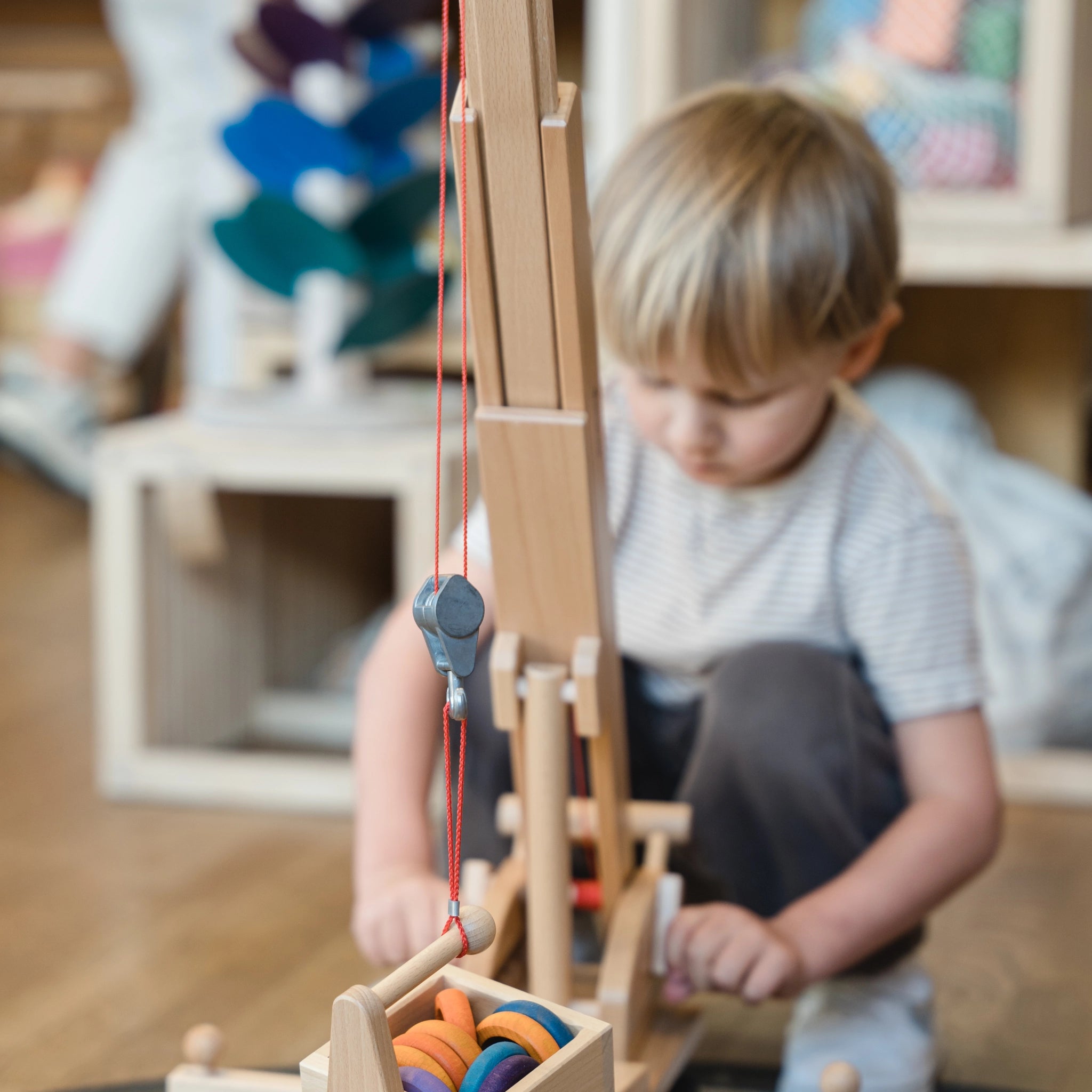 Zubehör: Ladegabel für Kran, aus massivem Buchenholz, wird von einem Kind spielerisch genutzt. Kompatibel mit Hoch- und Mobilkran, hergestellt in Deutschland, symbolisiert nachhaltige Produktion und modernes Design bei KLICKKLACK.