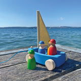 Holzfahrzeug: Strandsegler, ein schwimmfähiges Spielzeugset aus einem blauen Boot mit Segel und vier Holzfiguren, ideal für drinnen und draußen, von einer deutschen Manufaktur gefertigt.