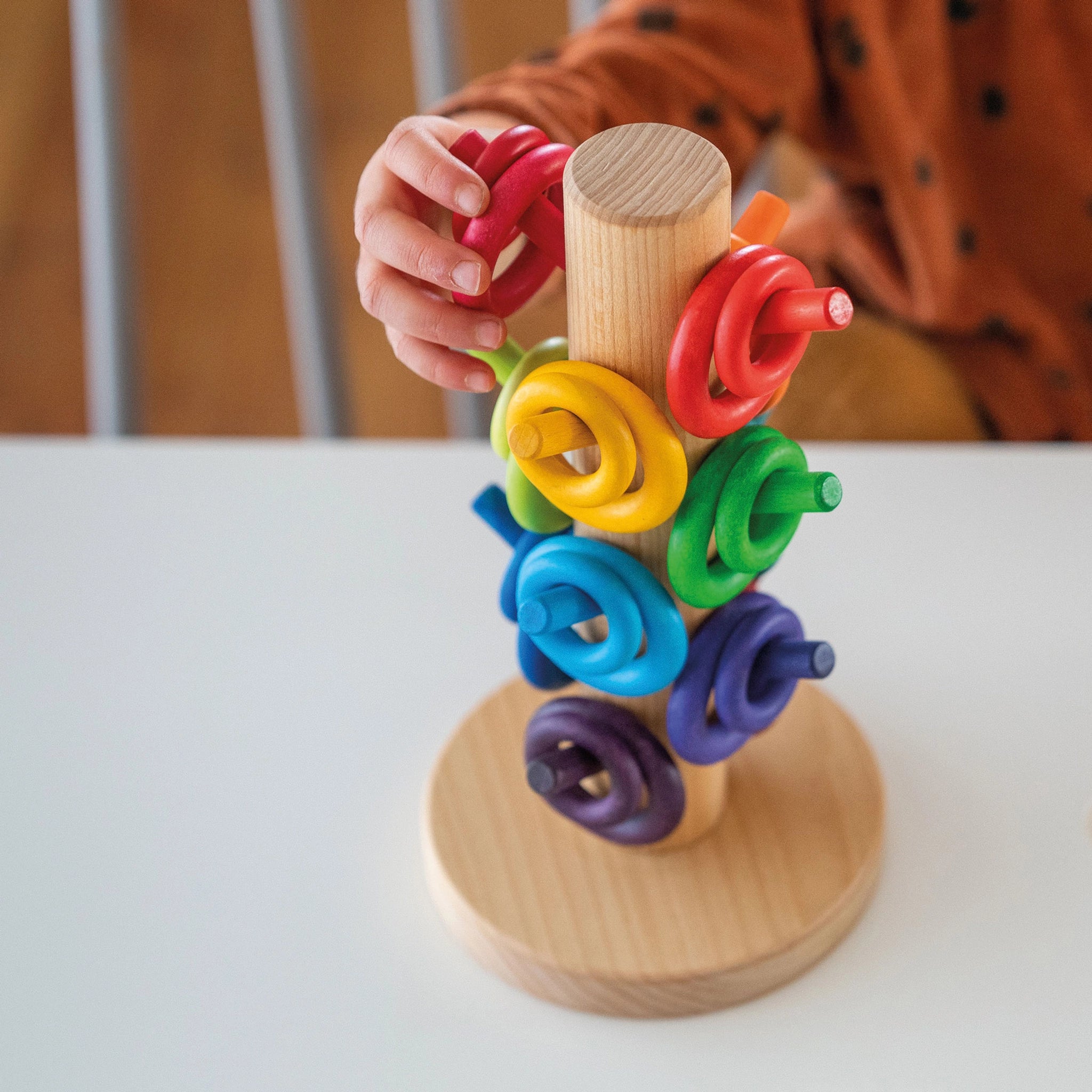 Kind spielt mit Freies Spiel: Sortierhilfe Bauringe Regenbogen, einem Holzspielzeug aus geöltem Buchen- und Erlenholz mit 12 bunten Dübeln, hergestellt in einer deutschen Manufaktur.