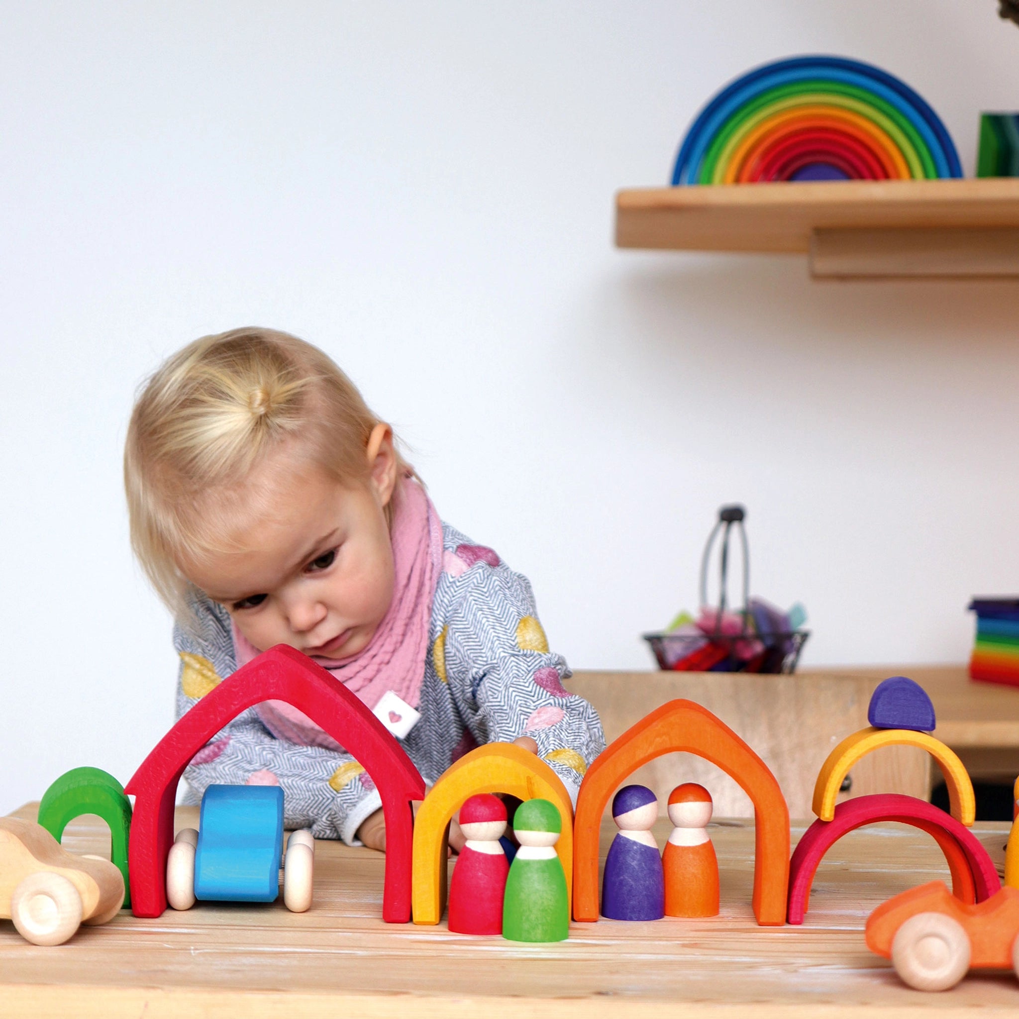 Freies Spielen: Buntes Haus aus hochwertigem Lindenholz, gezeigt beim Spielen eines Kindes. Das Set mit 5 elementaren, farbigen Teilen eignet sich perfekt zum Stapeln, Bauen und Sortieren.