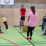 Teamspiel: Strippensurfer in Aktion in einem Fitnessstudio, mit Personen, die Balance und Körperkoordination trainieren. Das Produkt fördert Mut, Kraft und Vertrauen in einer Gruppe von 6 bis 22 Spielern.