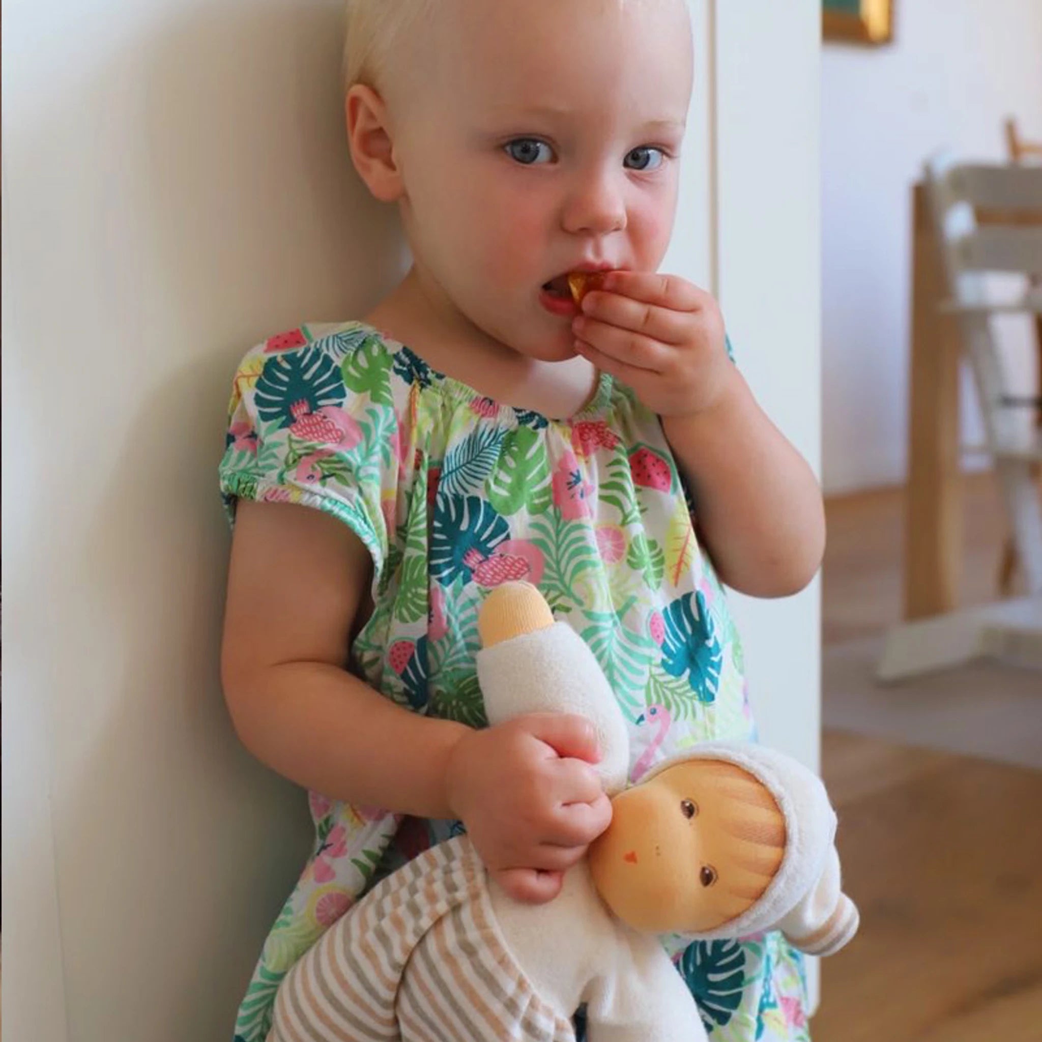 Ein Kind hält die Puppe: Möpschen natur gestreift, gefertigt aus weichem Bio-Baumwollfrottee mit schadstofffreier Schafschurwolle-Füllung, ideal als nachhaltiges Geschenk zur Geburt.