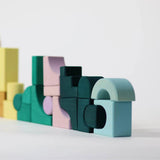 Bauwelt: Movement zeigt pastellfarbene, geometrische Holzbauklötze aus Lindenholz in Formen wie Bögen und Rechtecken. Teil von Grimm's TINY ART COLLECTION, fördern sie kreatives, experimentelles Bauen.