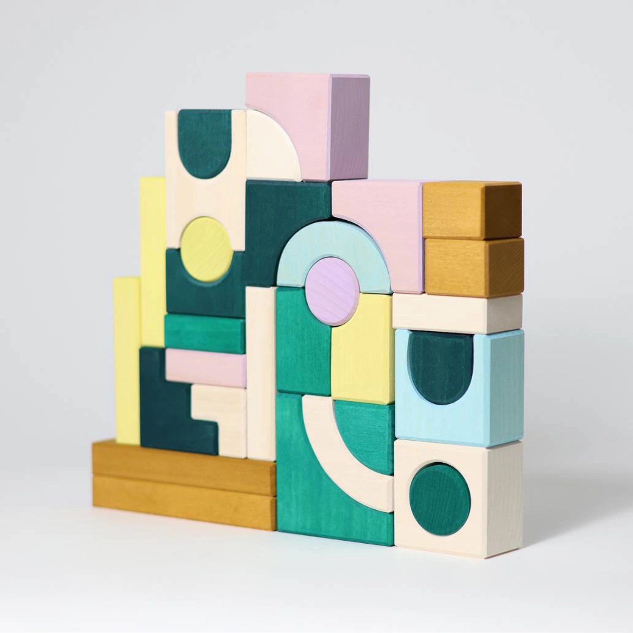 Bauwelt: Movement, ein abstrakter Baukasten aus farbig lasiertem Lindenholz, zeigt präzise gestapelte geometrische Formen für kreatives Bauen, Teil von Grimm's TINY ART COLLECTION, handgefertigt in Deutschland.