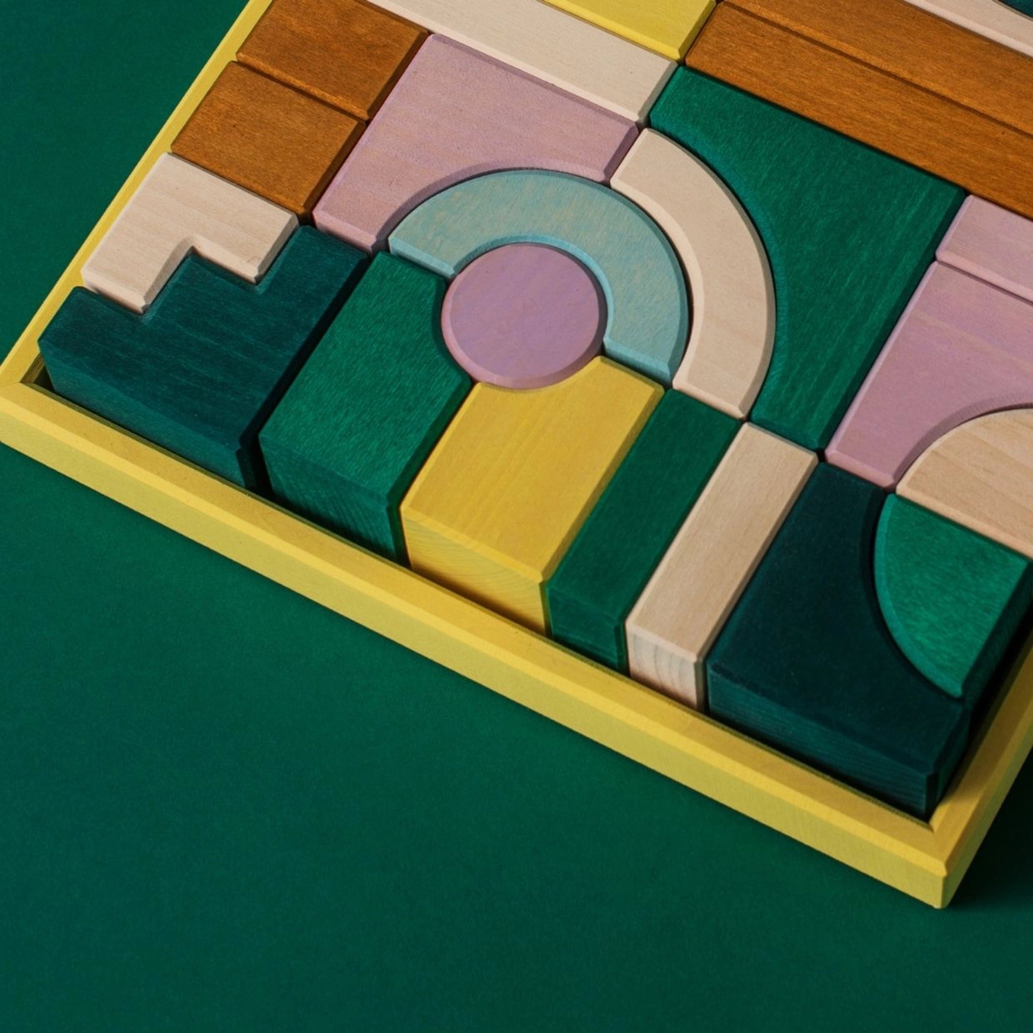 Bauwelt: Movement, ein Set aus bemalten Holzbausteinen, präsentiert geometrische Formen auf grünem Untergrund. Teil von Grimm's TINY ART COLLECTION, ideal für kreatives, experimentelles Bauen und in Deutschland nachhaltig hergestellt.