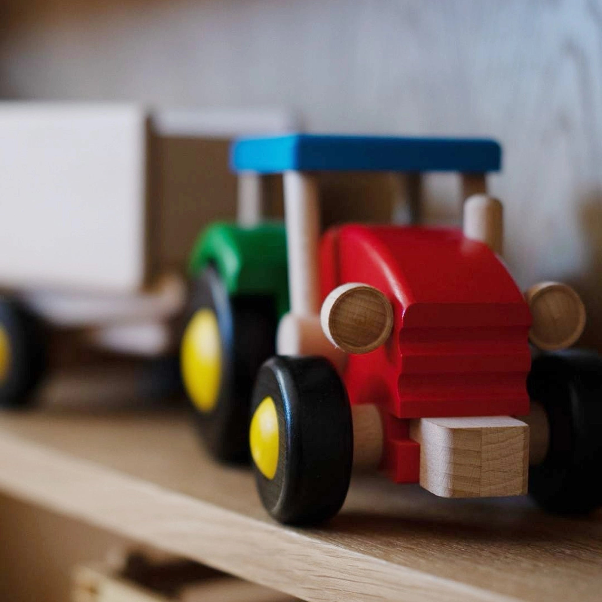 Holzfahrzeug: Traktor mit Anhänger aus robustem Buchen- und Ahornholz, mit abnehmbarem Anhänger und kippbarer Ladefläche, handgefertigt in einer polnischen Spielzeugmanufaktur, farbenfrohes Design, ideal für Kinder.