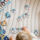 Puzzle: 10 Pinguine – Ein Kind spielt mit einem Puzzle aus FSC-Papier und recyceltem Karton, das aus 10 fortschreitenden Puzzles von 2 bis 10 Teilen mit niedlichen Tiermotiven besteht.