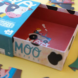 Puzzle: Moo - Puzzlebox mit Bild eines Jungen auf einem Traktor, umgeben von Bauernhof-Szenen. Enthält 36 große Teile aus FSC-Papier und recyceltem Karton, ideal für Kinder ab 3 Jahren.