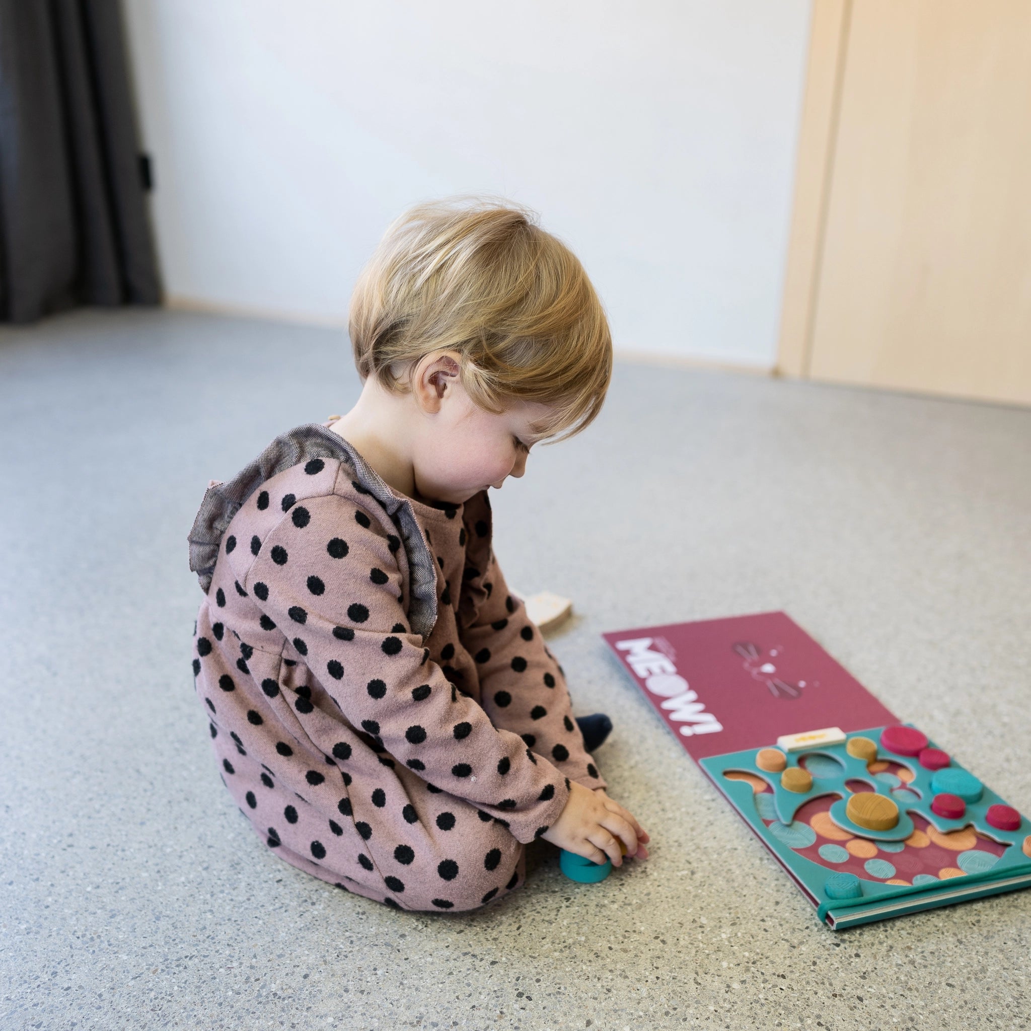 Kind spielt auf dem Boden mit dem Balancespiel: Meow aus Birkenfurnier und massivem Buchenholz, fördert Feinmotorik und Geschicklichkeit, geeignet für Kinder ab 5 Jahren.