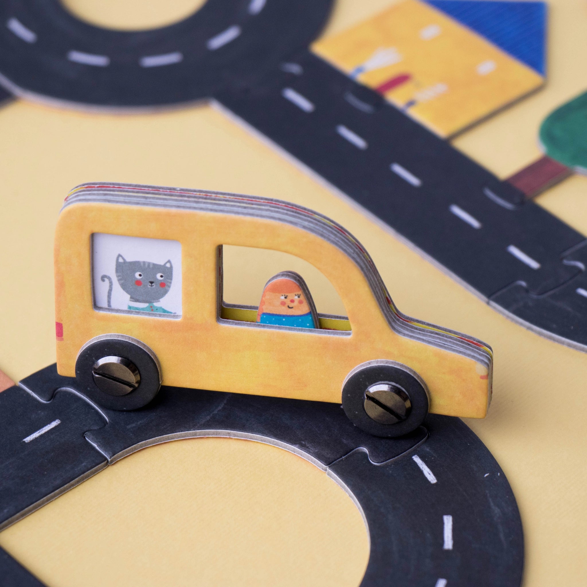 Gesellschaftsspiel: Roads, ein kreatives Legespiel aus FSC-Papier und recyceltem Karton, gezeigt mit einem Holzspielzeugauto auf einer Straße, ideal für Familien- oder Solospiel. Enthält sechs Spielautos.