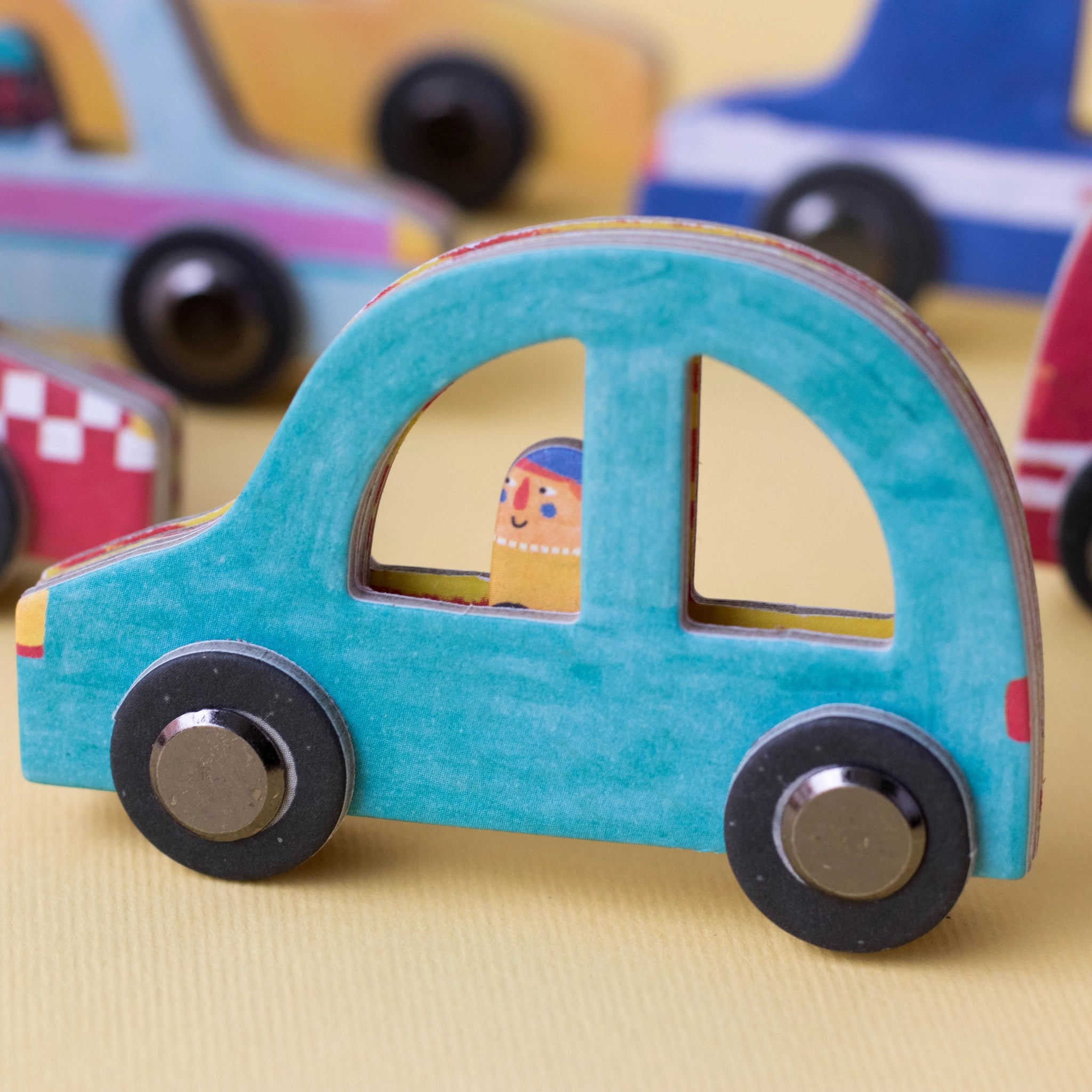 Gesellschaftsspiel: Roads zeigt ein blaues Spielzeugauto mit Figur im Fenster, Teil eines kreativen Legespiels aus nachhaltigen Materialien. Ideal für Familien- oder Solospiel, in Spanien handgefertigt.