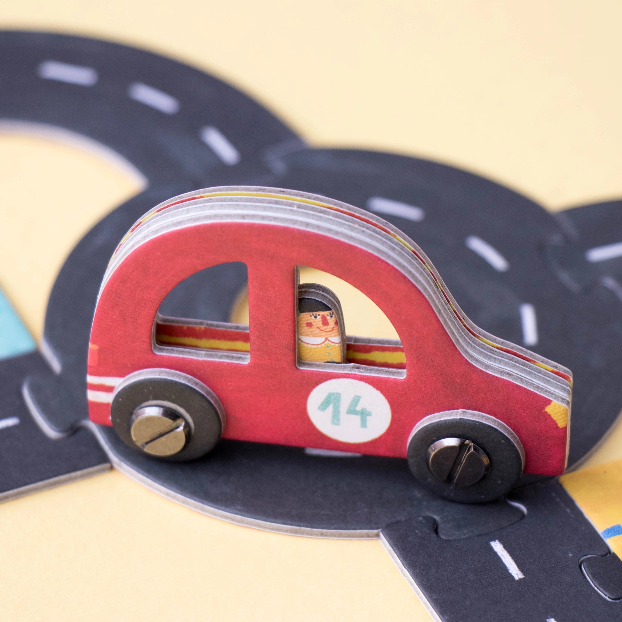 Gesellschaftsspiel: Roads zeigt ein kreatives Legespiel mit einem Spielbrett und Miniaturautos. Hergestellt aus FSC-Papier und recyceltem Karton, ideal für Familien- oder Solospiele, produziert in Spanien.