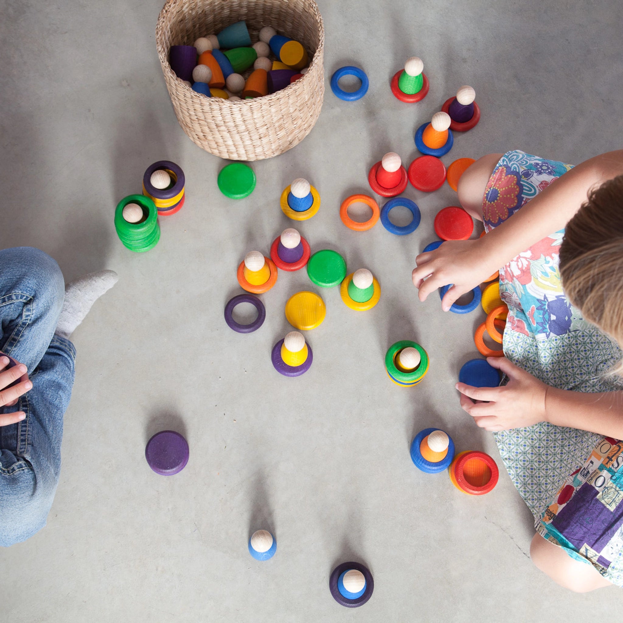 Freies Spiel: Nins, Rings & Coins, zwei Kinder spielen mit handgefertigten Holzfiguren, Ringen und Plättchen. Nachhaltig produziert, fördert kreatives Spielen. Passend zu KLICKKLACKs ästhetischem und nachhaltigem Ansatz.