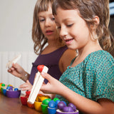 Freies Spiel: Bowls & Acorns – Kinder spielen mit handgefertigtem Holzsortierspiel, bestehend aus sechs Schälchen, 36 Eicheln und Holzzange, ideal für kreatives Spiel.