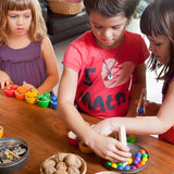 Freies Spiel: Bowls & Acorns – Kinder spielen mit handgefertigtem Holzsortierspiel aus Spanien, bestehend aus sechs Schälchen, 36 Eicheln und einer Holzzange, ideal für kreatives, freies Spiel.