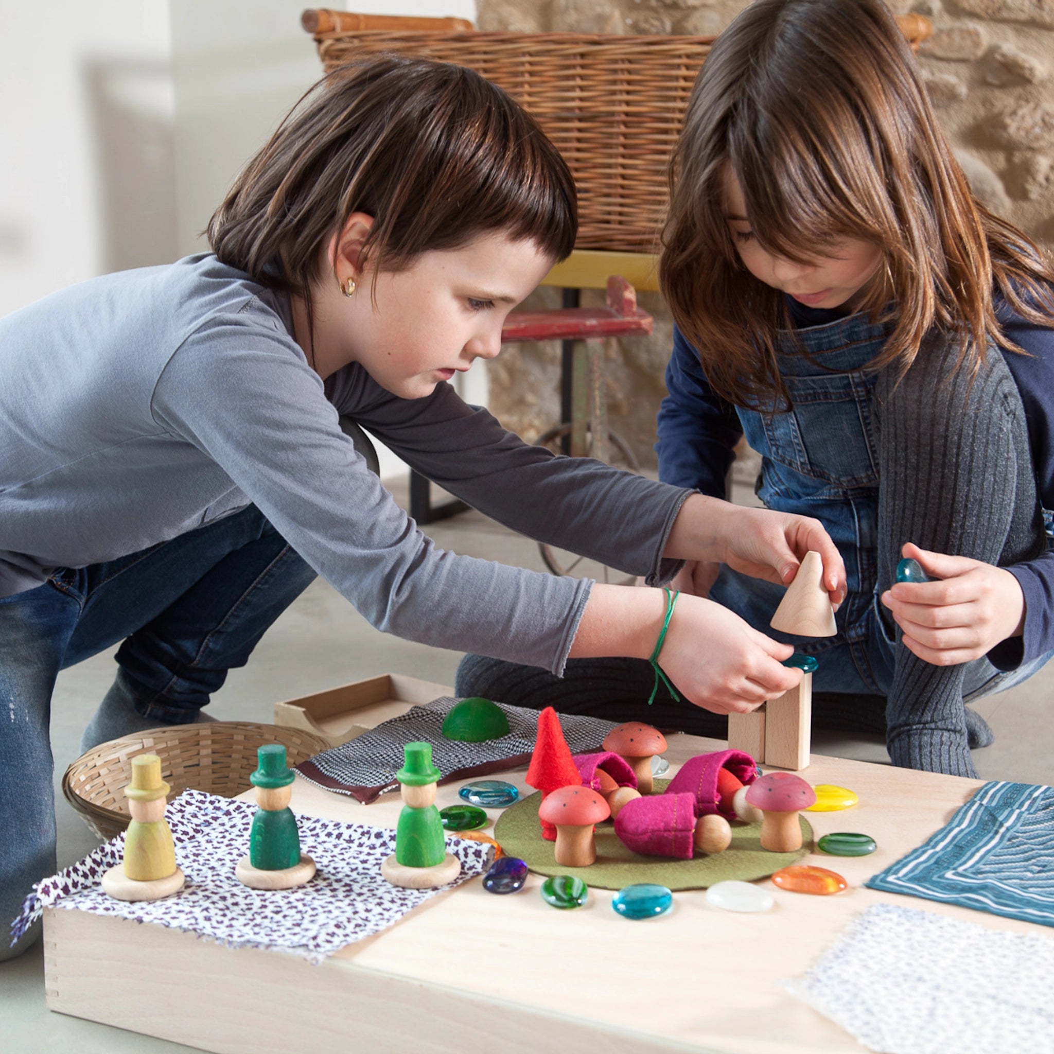 Freies Spiel: Nins of the Forest – Kinder spielen mit handgefertigten, nachhaltigen Nins-Figuren und Waldzubehör aus Holz auf einem Tisch, ideal für kreatives, freies Spiel.