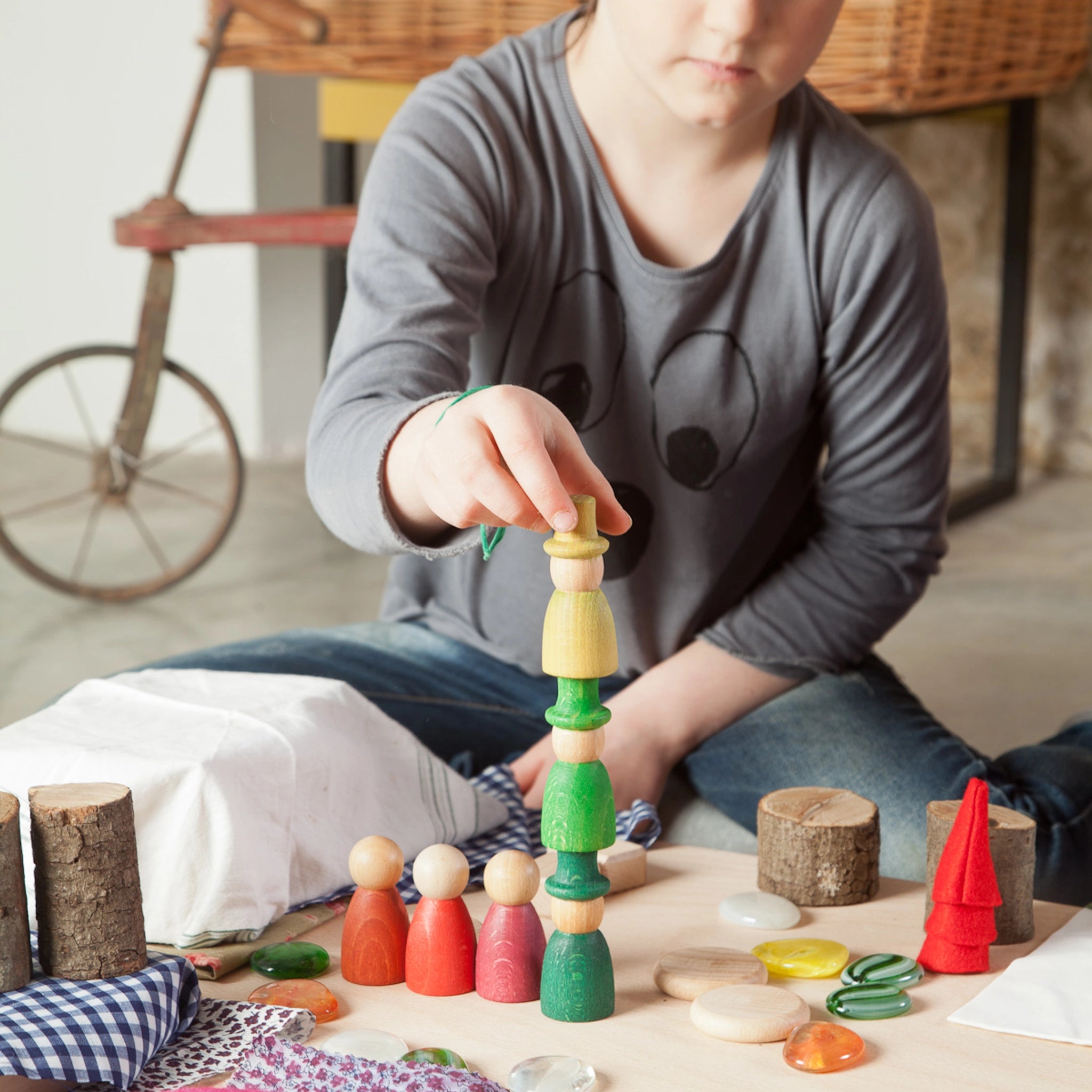 Freies Spiel: Nins of the Forest – Ein Mädchen spielt mit handgefertigten Holzfiguren aus nachhaltiger Forstwirtschaft. Das Set umfasst 6 Nins-Figuren mit Zylindern, Filzhüten und Waldzubehör, ideal für kreatives Spiel.