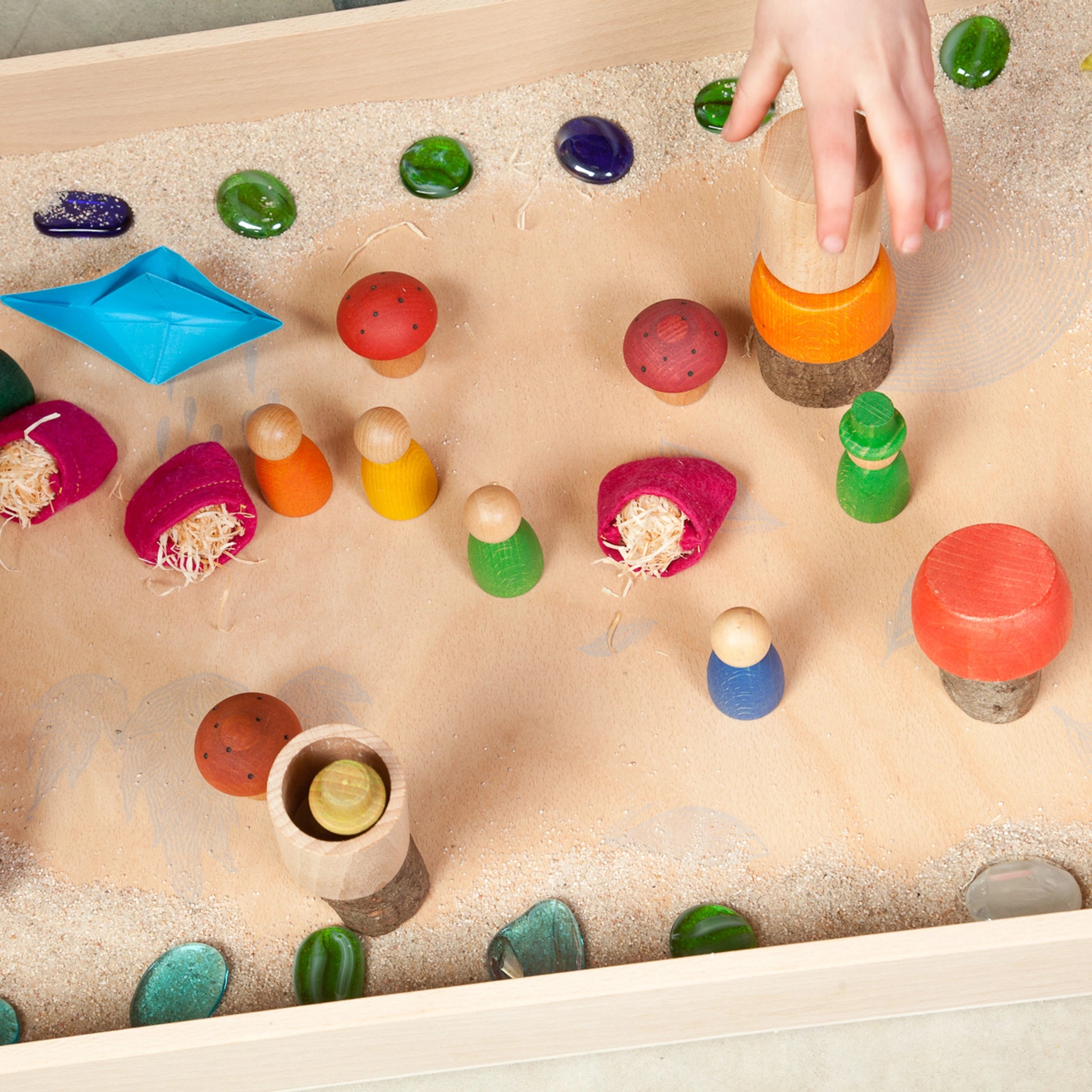 Freies Spiel: Play Box aus nachhaltig geerntetem Holz, ideal für sensorische und freie Spiele. Bild zeigt eine Hand, die ein hölzernes Spielzeug berührt, passend zum Montessori-Konzept.