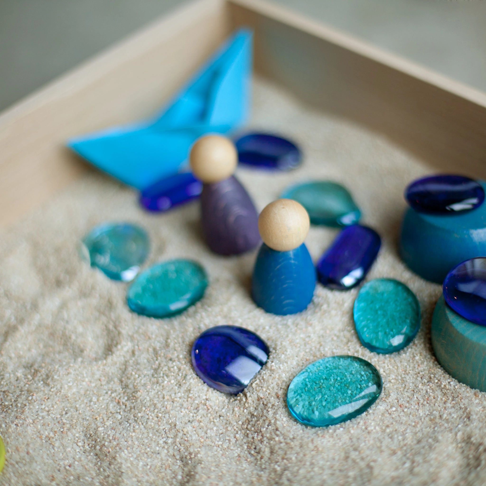 Freies Spiel: Play Box mit handgefertigten, hölzernen Figuren in einem Sandkasten, inspiriert vom Montessori-Konzept, ideal für sensorische und kreative Spiele. Nachhaltig in Spanien produziert.