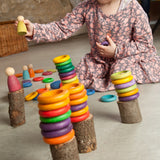 Mädchen spielt mit Freies Spiel: Nins Carla, einem Set aus nachhaltig gefertigtem Holzspielzeug, bestehend aus bunten Ringen und Figuren, ideal für kreatives, freies Spiel.