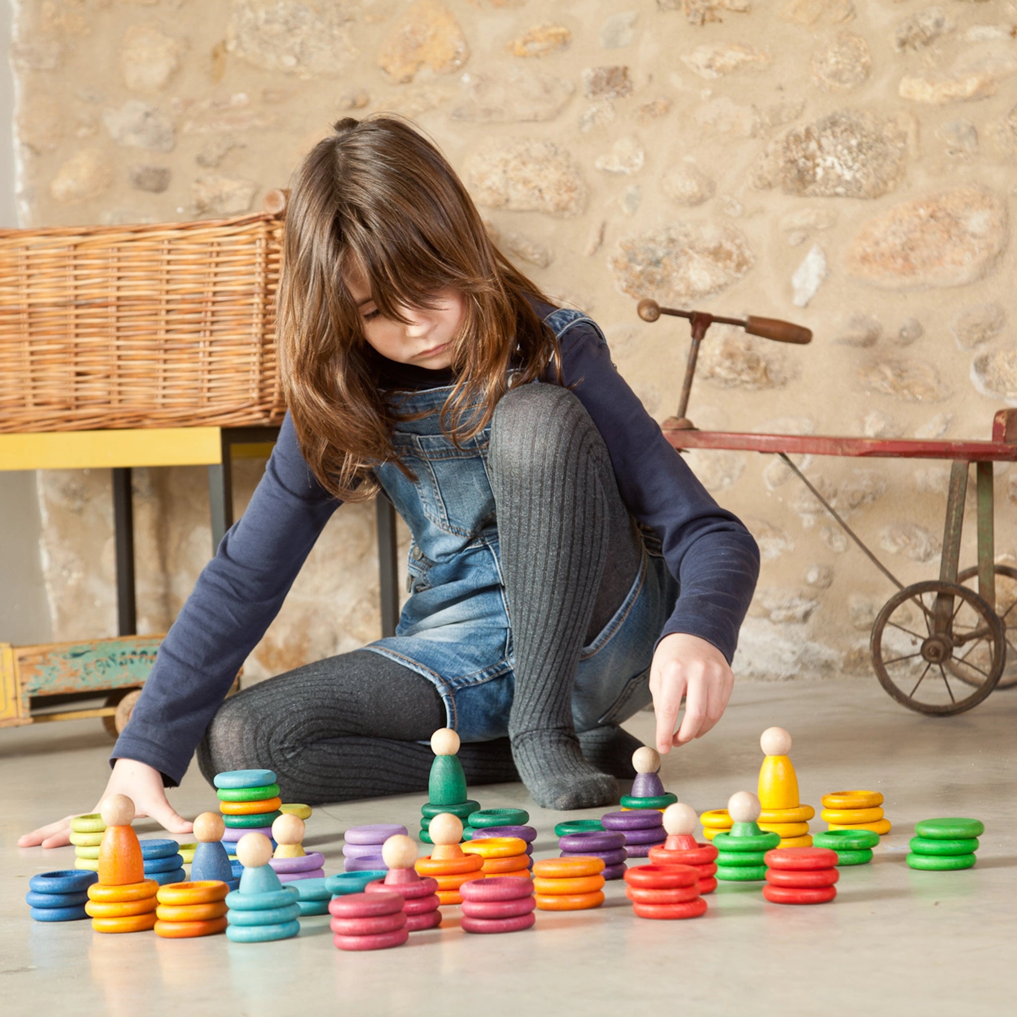 Mädchen spielt mit Freies Spiel: Nins Carla – ein handgefertigtes Set aus Holzringen und Figuren, ideal für kreatives Kinderspiel. Nachhaltiges Design von KLICKKLACK, fördert fantasievolles Spielen.