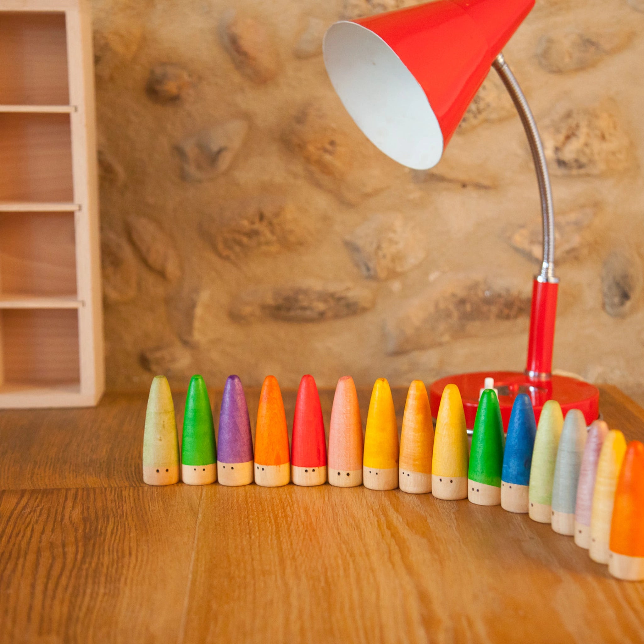 Freies Spiel: Sticks, ein Set aus 18 handgefertigten, bunten Holzfiguren mit dezentem Gesicht, ideal für kreatives Kinderspiel. Nachhaltig in Spanien produziert und auf einem Tisch präsentiert.